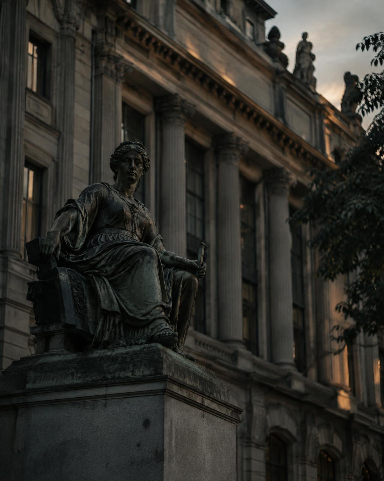 Bronze sculpture before a historic exchange building at dusk
